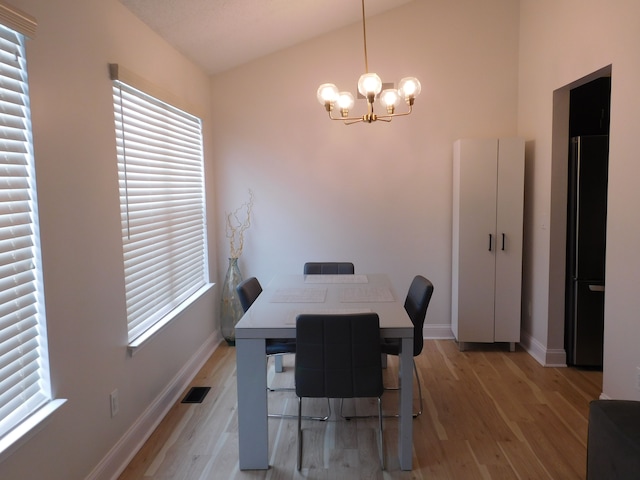 dining space featuring lofted ceiling, a notable chandelier, and light hardwood / wood-style flooring