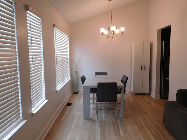 dining space featuring lofted ceiling, light hardwood / wood-style floors, and a chandelier