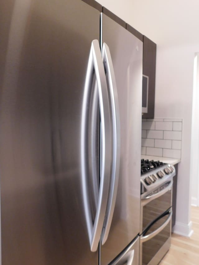 kitchen with stainless steel appliances, backsplash, and light hardwood / wood-style flooring