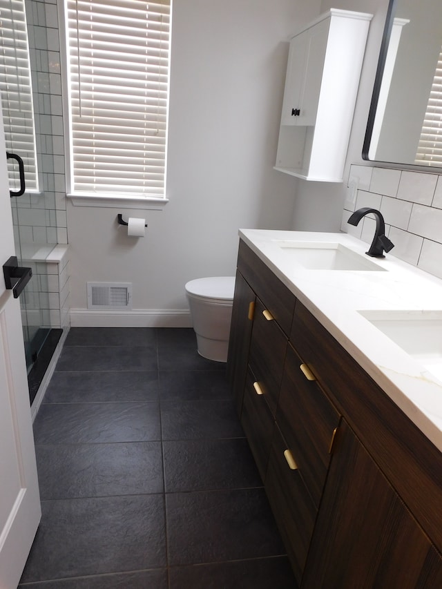 bathroom featuring vanity, tasteful backsplash, a shower with door, and toilet