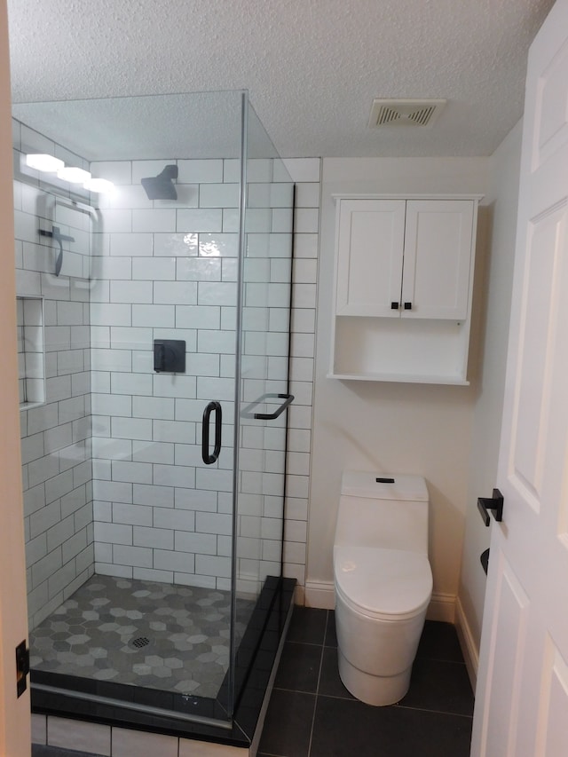 bathroom featuring a textured ceiling, a shower with shower door, tile patterned floors, and toilet