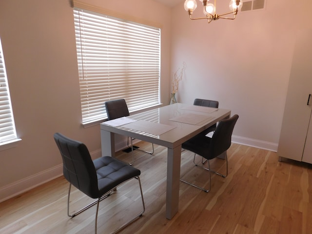 dining area with light hardwood / wood-style floors and a chandelier