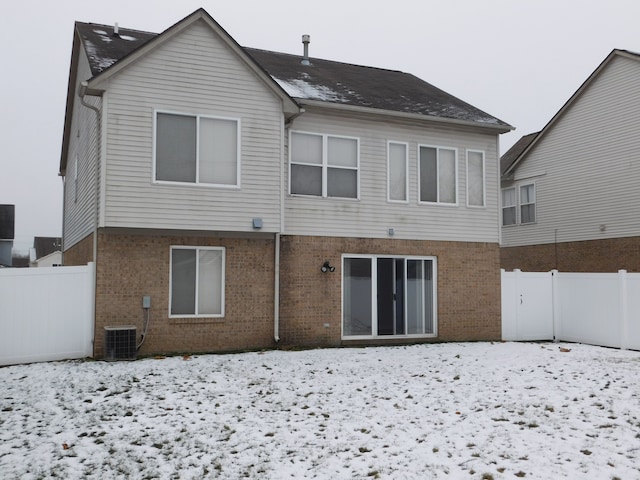 snow covered back of property featuring central air condition unit