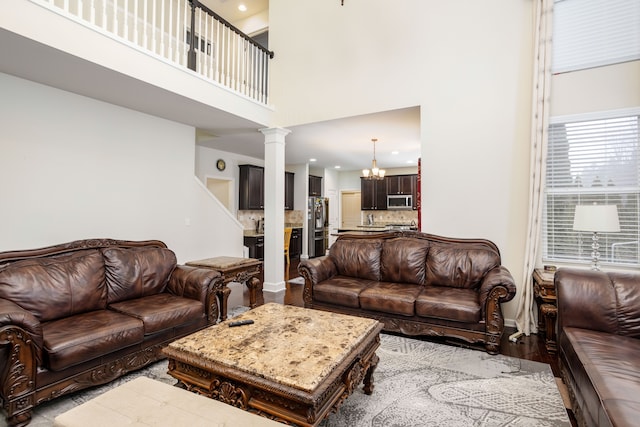 living room featuring an inviting chandelier, a high ceiling, light hardwood / wood-style flooring, and ornate columns