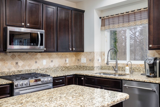 kitchen with dark brown cabinetry, sink, light stone counters, appliances with stainless steel finishes, and decorative backsplash