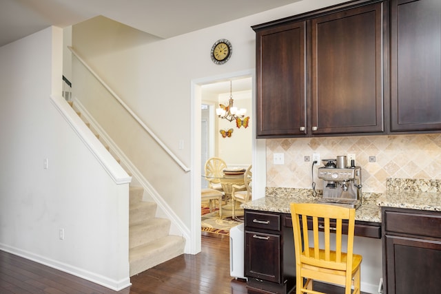 kitchen featuring light stone counters, backsplash, dark brown cabinetry, and dark hardwood / wood-style floors