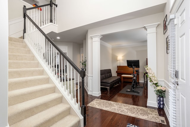 entrance foyer featuring ornate columns, crown molding, dark hardwood / wood-style floors, and a towering ceiling