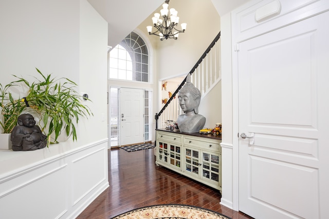 foyer with an inviting chandelier, a towering ceiling, and dark hardwood / wood-style floors