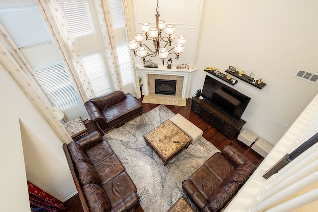 living room with an inviting chandelier, a premium fireplace, and dark wood-type flooring