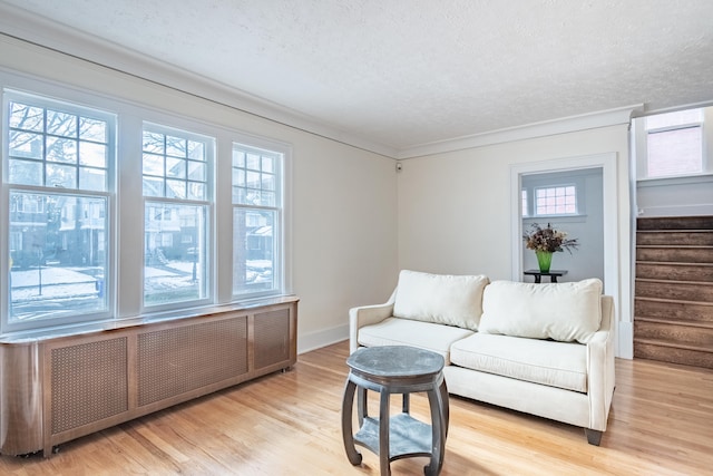 living room featuring radiator heating unit, a textured ceiling, and light wood-type flooring