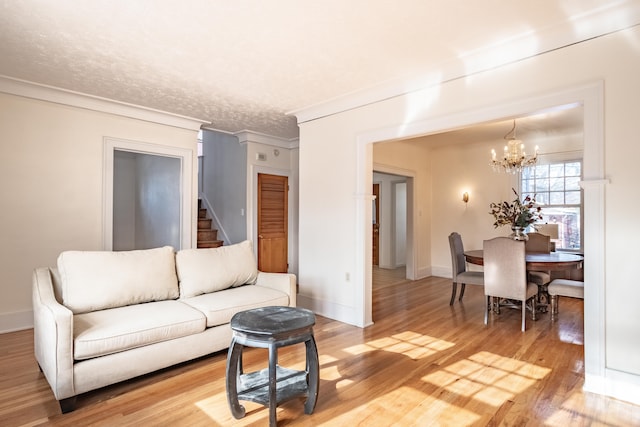 living room featuring hardwood / wood-style flooring, ornamental molding, a notable chandelier, and a textured ceiling