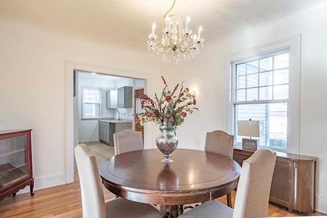 dining space featuring sink, light hardwood / wood-style floors, and a chandelier