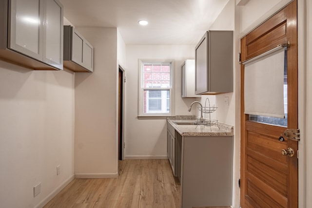 kitchen with gray cabinets, sink, and light hardwood / wood-style flooring