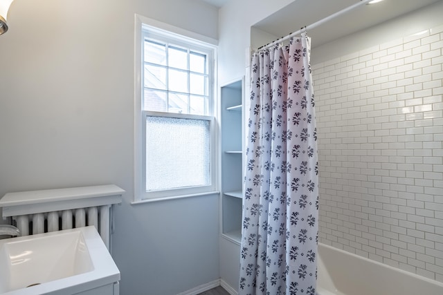 bathroom with shower / tub combo with curtain, a healthy amount of sunlight, and sink