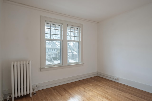 unfurnished room with radiator heating unit and light hardwood / wood-style flooring