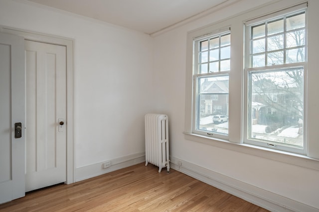 spare room featuring ornamental molding, radiator, and light hardwood / wood-style flooring