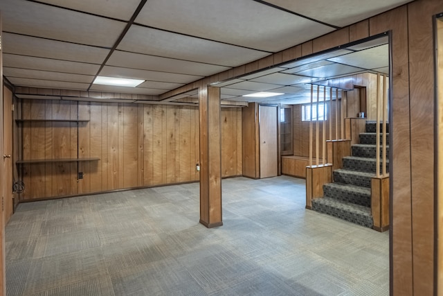 basement with a drop ceiling and wood walls