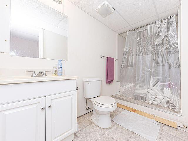 bathroom featuring vanity, a shower with shower curtain, a drop ceiling, and toilet