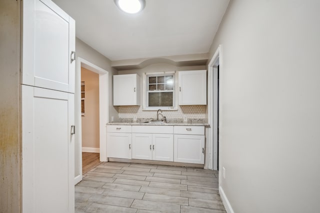 kitchen featuring white cabinetry, sink, tasteful backsplash, and light hardwood / wood-style flooring