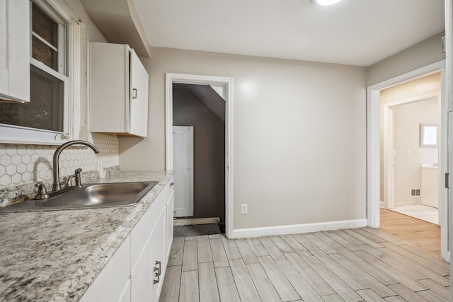 kitchen featuring white cabinetry, sink, decorative backsplash, and light hardwood / wood-style flooring