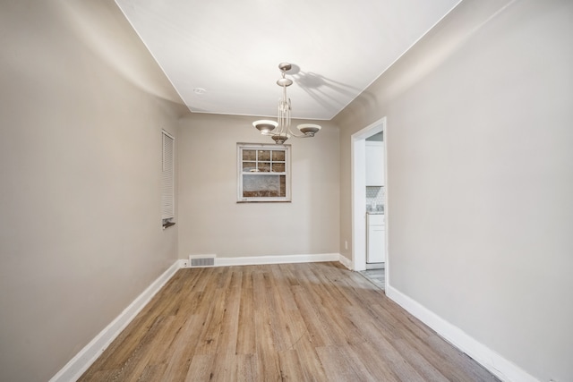 unfurnished dining area with an inviting chandelier and light wood-type flooring