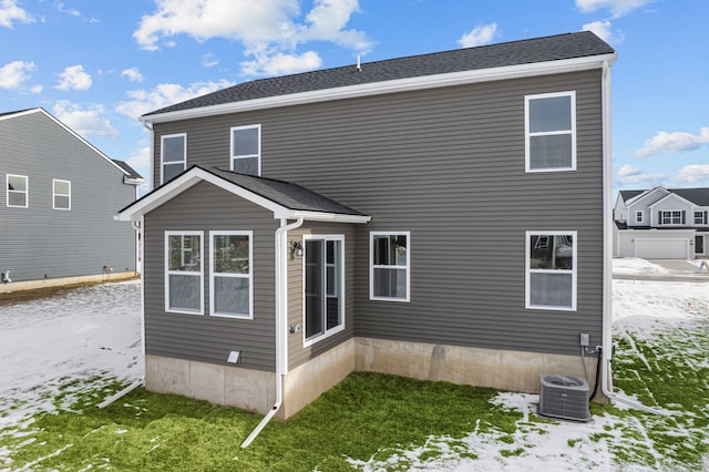 rear view of property featuring central air condition unit and roof with shingles