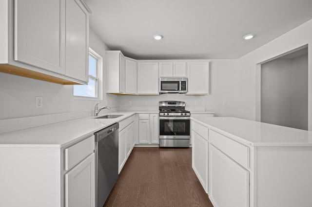 kitchen featuring a sink, stainless steel appliances, dark wood-type flooring, light countertops, and white cabinetry