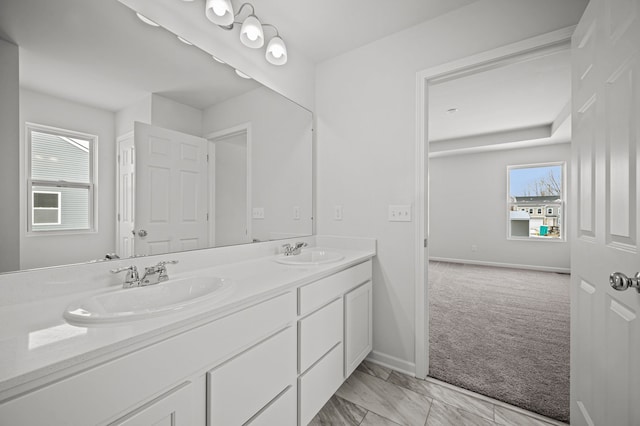 full bathroom with a sink, baseboards, marble finish floor, and double vanity