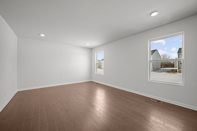 unfurnished room with dark wood-type flooring, recessed lighting, baseboards, and visible vents