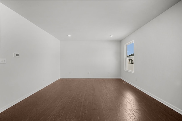 spare room featuring dark wood-style floors, recessed lighting, and baseboards