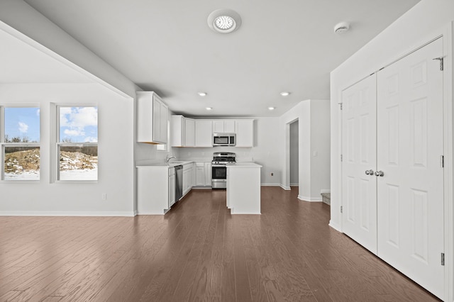 kitchen with dark wood-style floors, stainless steel appliances, white cabinets, light countertops, and baseboards