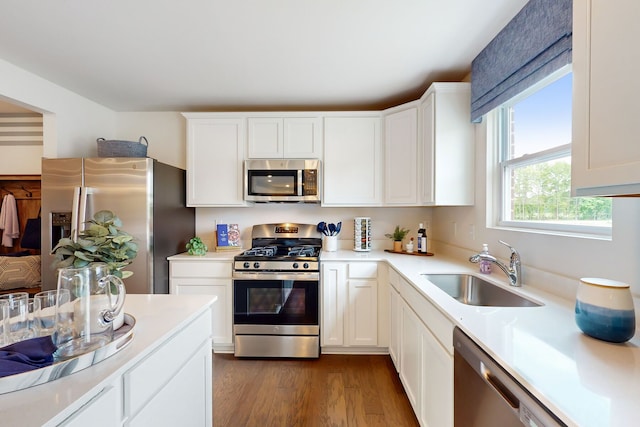 kitchen with a sink, light countertops, white cabinets, stainless steel appliances, and dark wood-style flooring