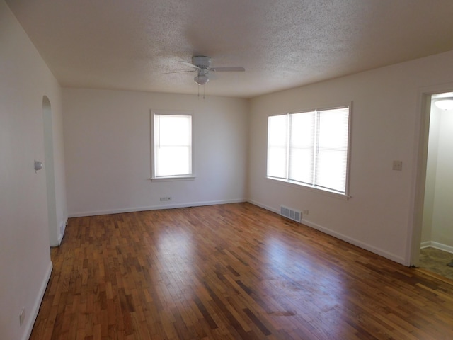 1336 Agard Ave, Benton Harbor, MI 49022 - spare room featuring arched walkways, a ceiling fan, baseboards, wood finished floors, and visible vents
