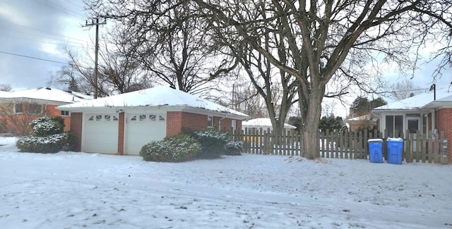 yard layered in snow featuring an outbuilding and a garage