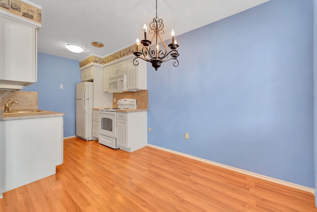 kitchen featuring sink, tasteful backsplash, white cabinetry, decorative light fixtures, and white appliances