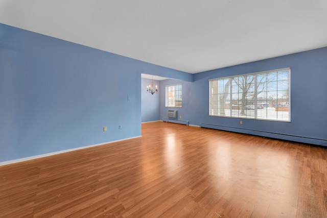 unfurnished room with light hardwood / wood-style flooring, a notable chandelier, and a baseboard radiator