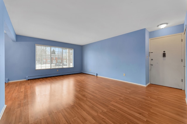 unfurnished room with a baseboard radiator and light hardwood / wood-style floors