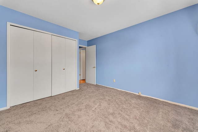 unfurnished bedroom featuring light carpet and a closet