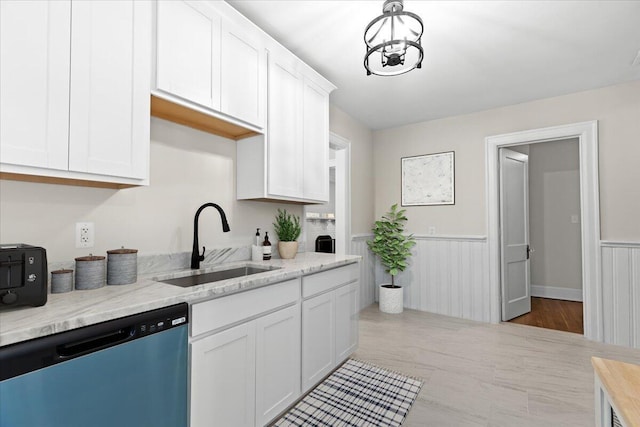 kitchen with white cabinetry, stainless steel dishwasher, light stone countertops, and sink