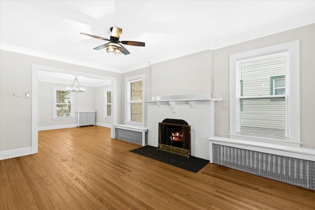 unfurnished living room with hardwood / wood-style flooring, crown molding, radiator, and a fireplace