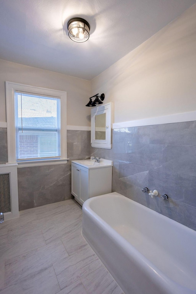 bathroom with a tub to relax in, vanity, and tile walls