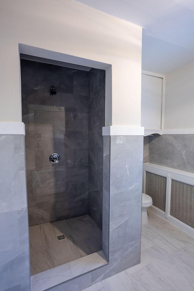 bathroom featuring a tile shower and toilet