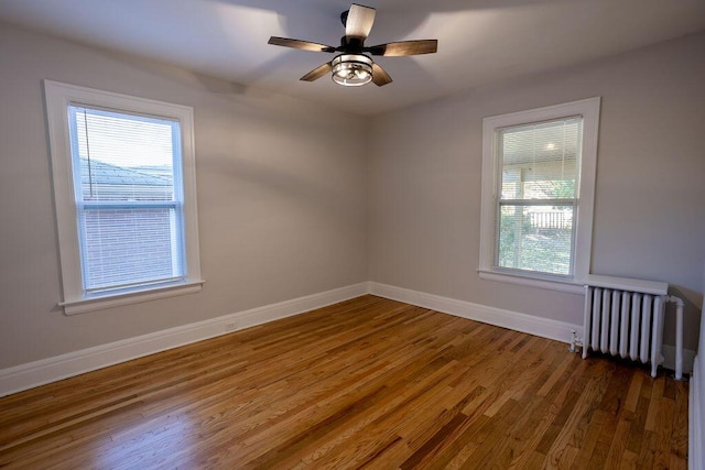 empty room featuring dark hardwood / wood-style flooring, radiator, and ceiling fan