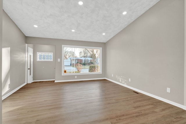 unfurnished living room with hardwood / wood-style flooring, lofted ceiling, and a textured ceiling