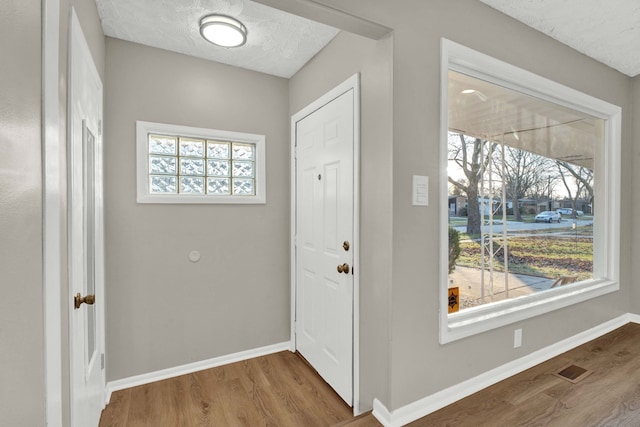 entryway with wood-type flooring and a textured ceiling