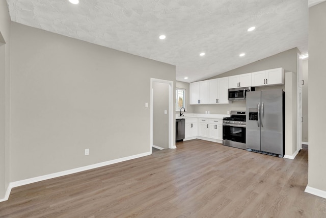 kitchen with lofted ceiling, sink, light hardwood / wood-style flooring, stainless steel appliances, and white cabinets