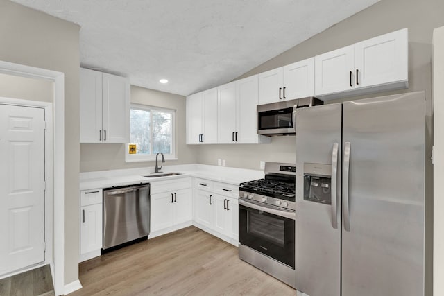 kitchen featuring white cabinetry, sink, light hardwood / wood-style floors, and appliances with stainless steel finishes