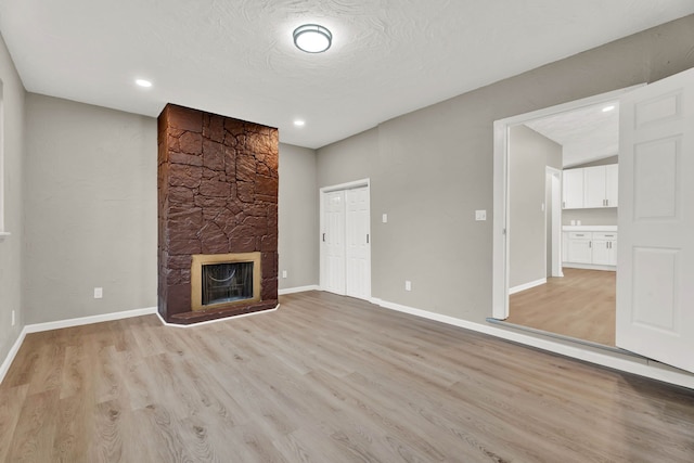 unfurnished living room featuring a textured ceiling, a fireplace, and light hardwood / wood-style floors