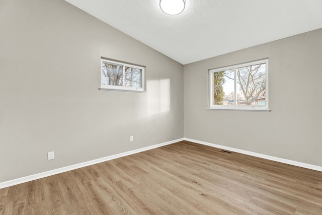 spare room with vaulted ceiling and light hardwood / wood-style floors