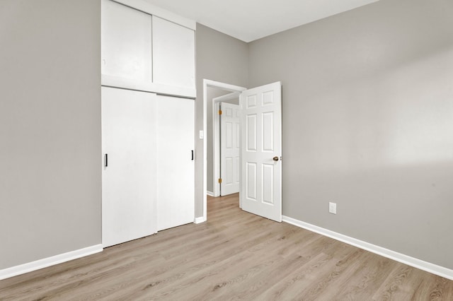 unfurnished bedroom featuring light wood-type flooring and a closet